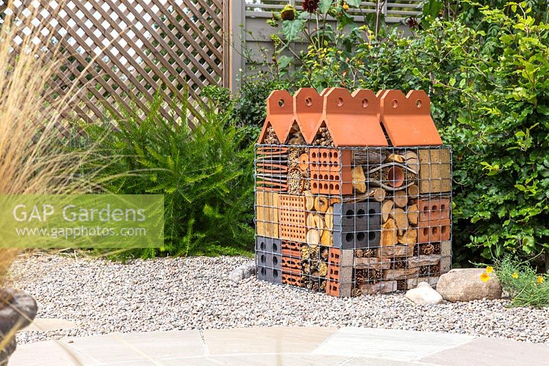 Insect hotel created in wire gabion with different building and dried plant materials