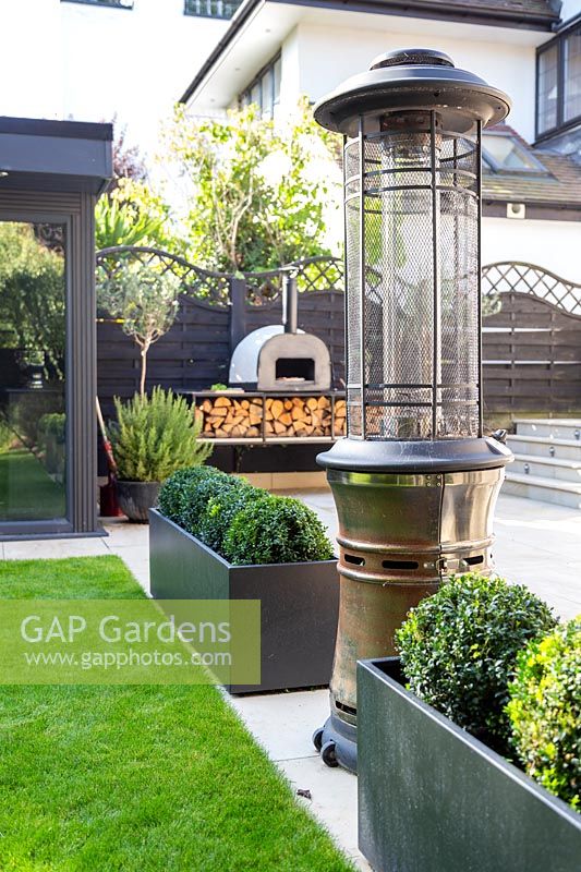 View past formal planters and patio heater to outdoor pizza oven. 