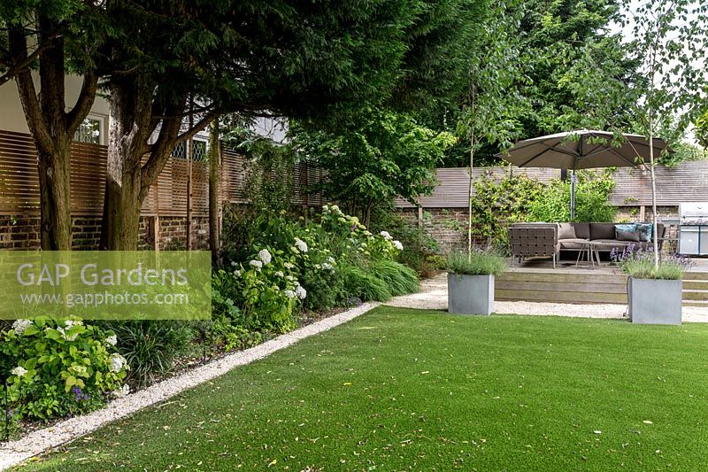 Large garden in St John's Wood with artificial lawn and raised deck seating area 

