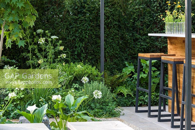 Bar with stools and Ferns, Agapanthus and Fatsia. 'Landform Garden Bar', RHS Hampton Flower Show, 2018