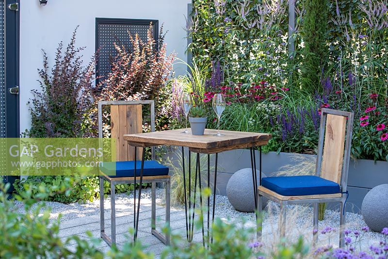 Outdoor dining area surrounded by mixed planting in a raised bed - Secured by Design, RHS Hampton Court Palace Flower Show 2018