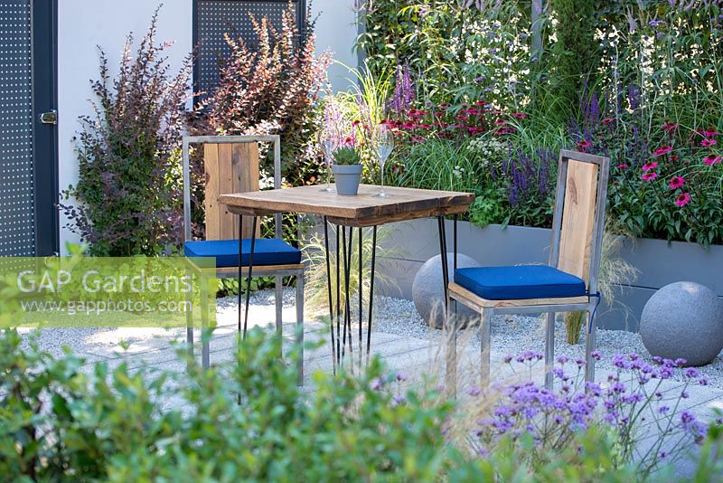 Outdoor dining area surrounded by planting in a raised bed - Secured by Design, RHS Hampton Court Palace Flower Show, 2018. 