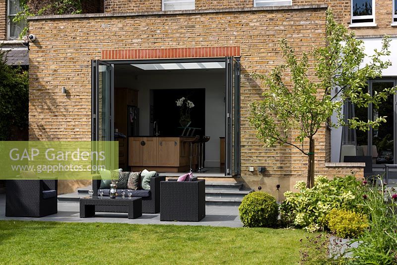 Lounge furniture on patio with view to house extension with bifold doors