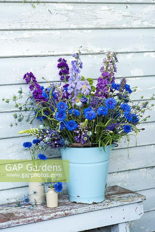 Blue themed summer floral display in blue enamel bucket.  