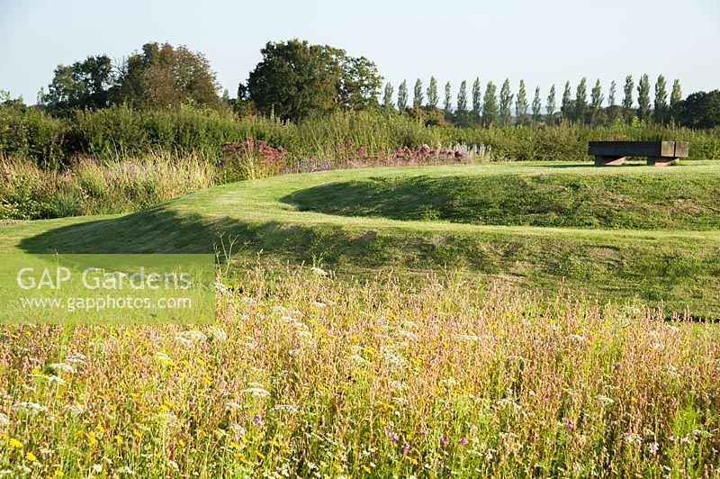 Annual meadow flowers with spiral earthwork. The Oast House, Isfield, Sussex, UK