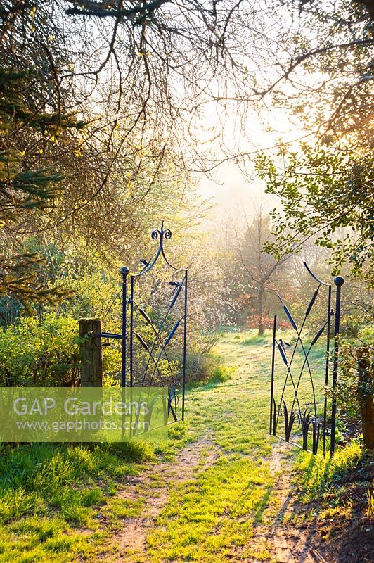 Gate by Dave Bissell with dragonflies and bulrushes. Moors Meadow Garden and Nursery, Bromyard, Herefordshire, UK