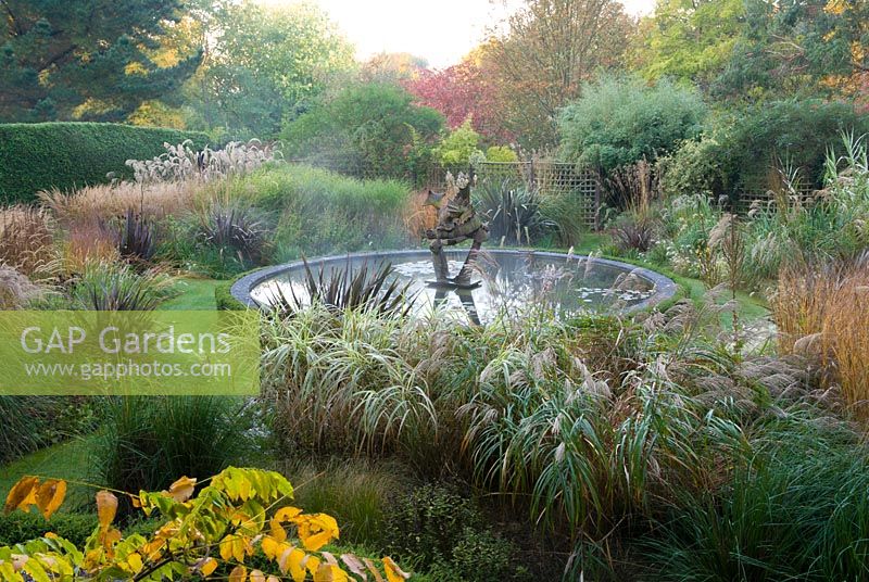 Dragon Garden with Central circular pond featuring dragon sculpture. Knoll Gardens, nr Wimborne, Dorset, UK