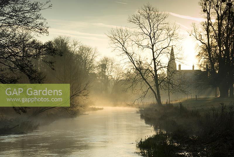 Morning sun on mist of River Lambourn at Welford Park, Newbury, Berkshire, UK. 