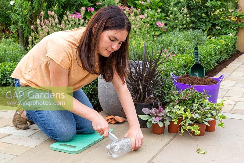 Woman cutting the bottom of a plastic water bottle with a hobby knife. 
