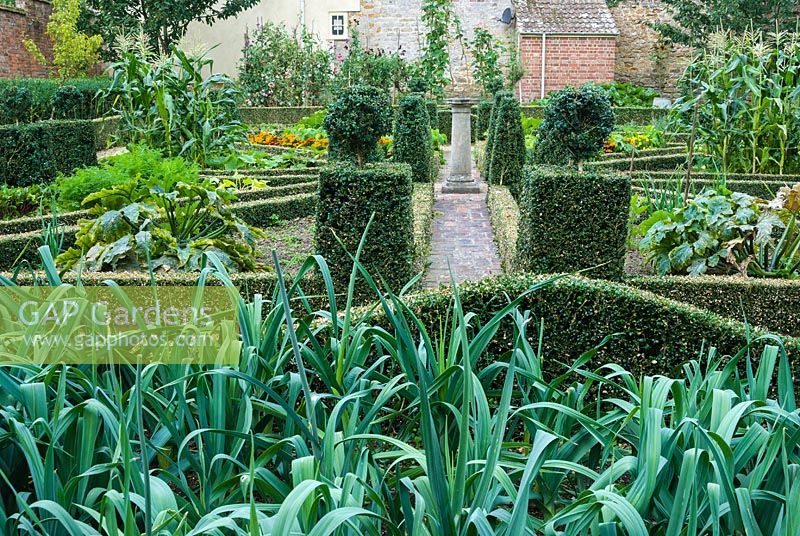 Walled kitchen garden with box edged beds and central sun dial. 