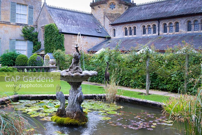 Decorative pond with fountain and Romanesque chapel behind. 