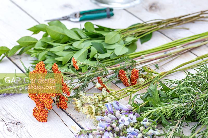 Ingredients for tying a mixed bouquet of garden flowers laid out on table. 