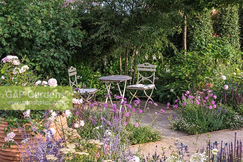 Tranquil courtyard edged in the soft pinks, purples and blues of roses, scabious and salvias. Best of Both Worlds, Sponsored by BALI, Hampton Court Flower Show, 2018.