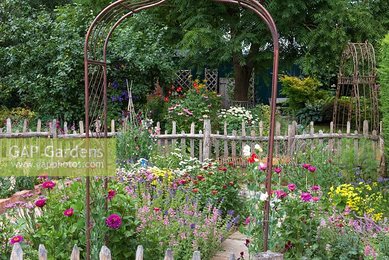 Metal arch sitting among cut flower beds. 