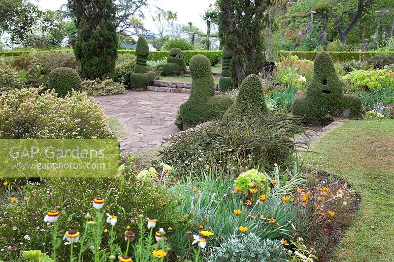 View across sunken paved garden with unusual topiary shapes
 