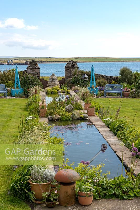 Running down the centre of this coastal garden is an 18-metre-long rill edged in flag irises, alchemilla, libertia, allium and phalaris.