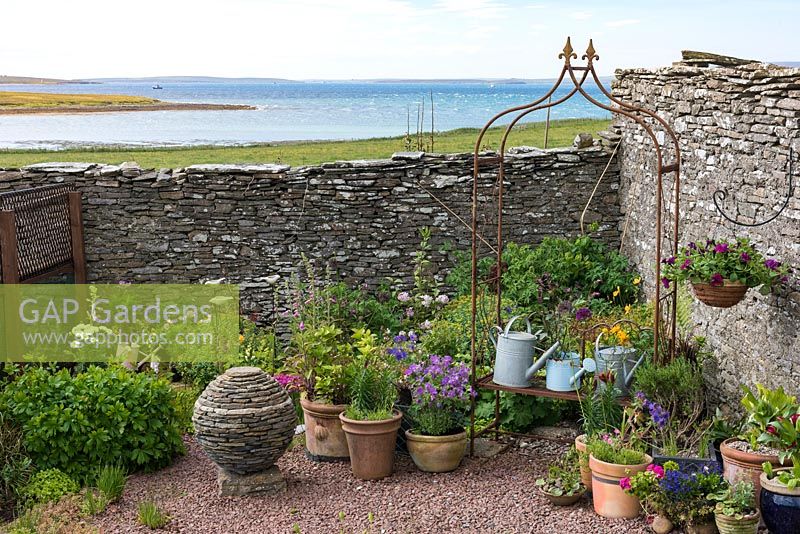 Tall dry stone wall wards off sea breezes from a small courtyard. 