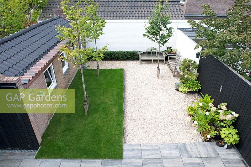 Overview of small patio garden with gravelled area and benches. 