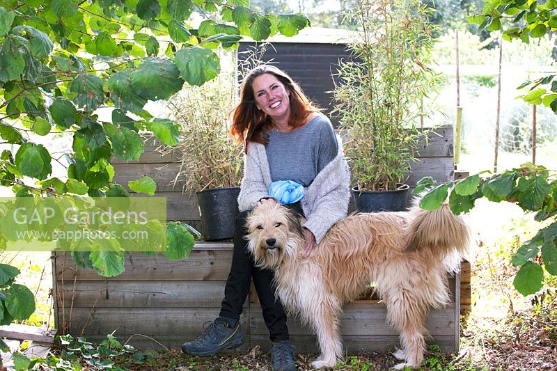 Yolanda van Velsen and her dog Sunny sitting on the wooden bench under a tree.