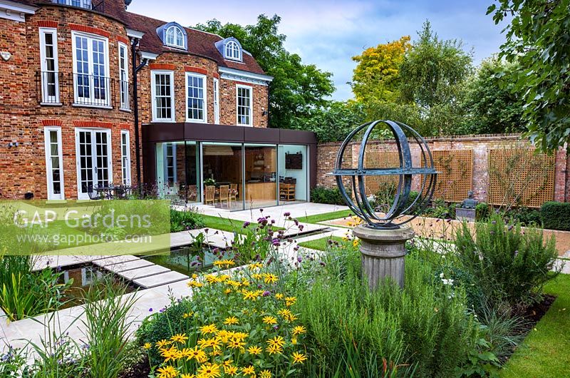 View accross Armillary Sundial and pond to the rear of the house. Garden design by Peter Reader Landscapes.