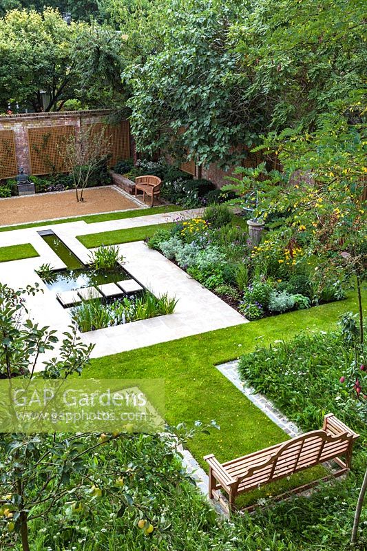 Overview of pond, mixed beds and wooden bench in contemporary city garden.  Garden design by Peter Reader Landscapes.