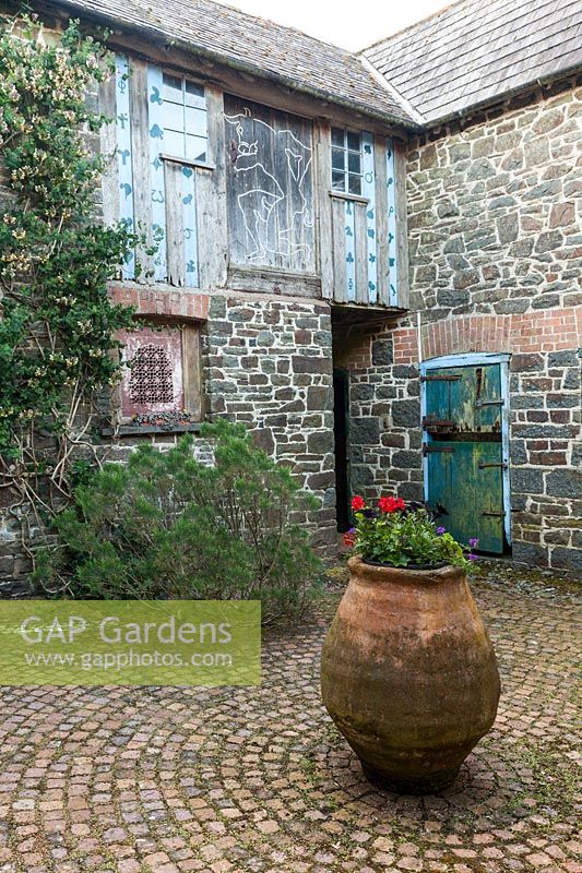 Central Greek terracotta pot in paved courtyard, Plaz Metaxu Garden, Devon, UK.