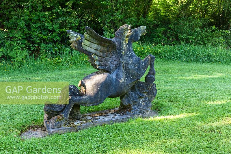 Stone sculpture of a winged horse on lawn. Plaz Metaxu Garden, Devon, UK. 