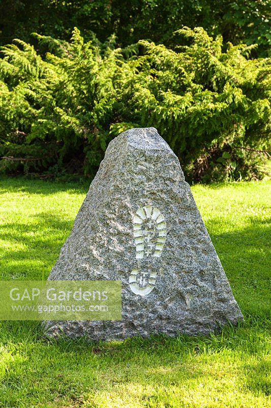 Stone with footprint at the entrance. Plaz Metaxu Garden, Devon, UK.