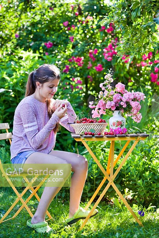 Girl enjoying cherries in the garden.
