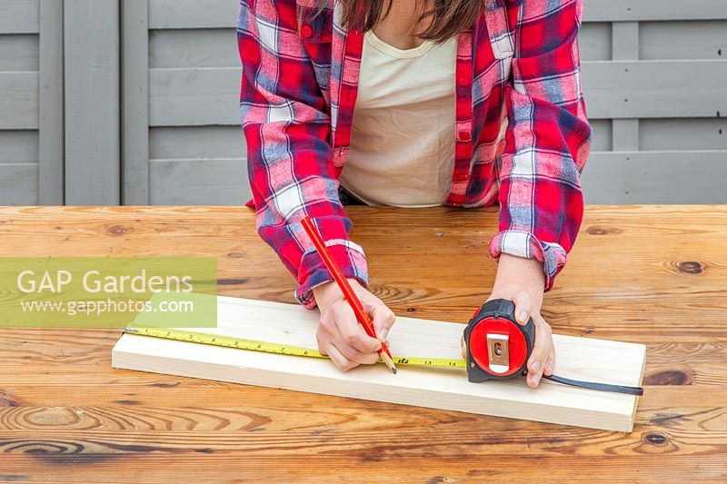 Using tape measure to mark along piece of wood.