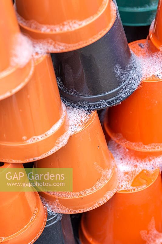 Stack of soapy plastic plant pots left to drain after washing