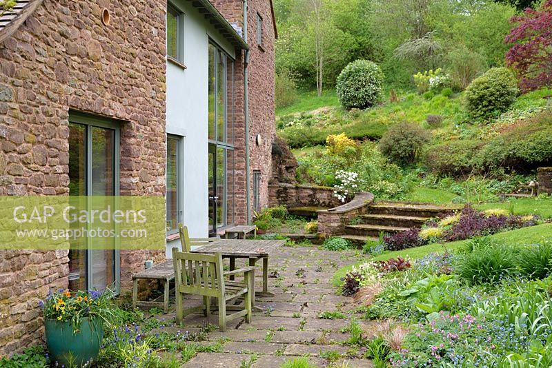 Terrace with table and chairs at back of house with ground cover planting, Ross-on-Wye