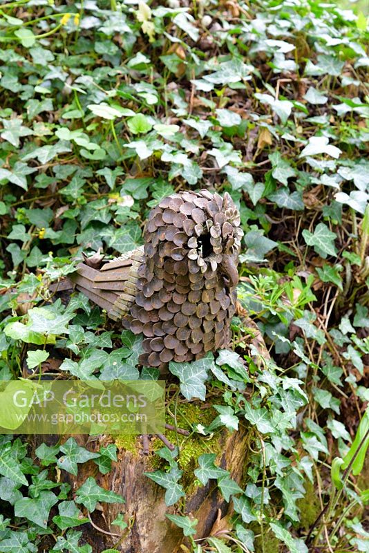 Metal owl sculpture on wooden post with Hedera - ivy, Ross-on-Wye, Herefordshire