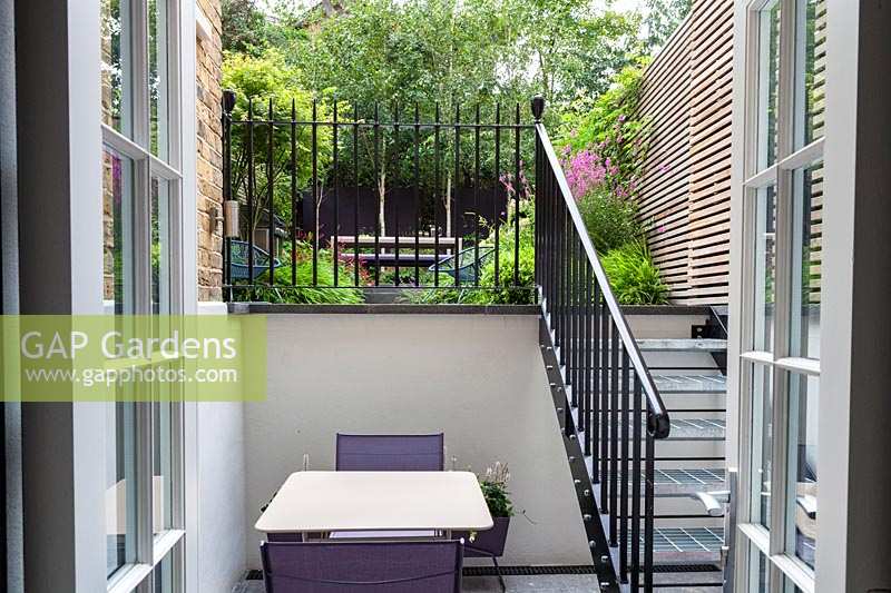 View through iron railings to garden beyond. Garden designed by John Davies.