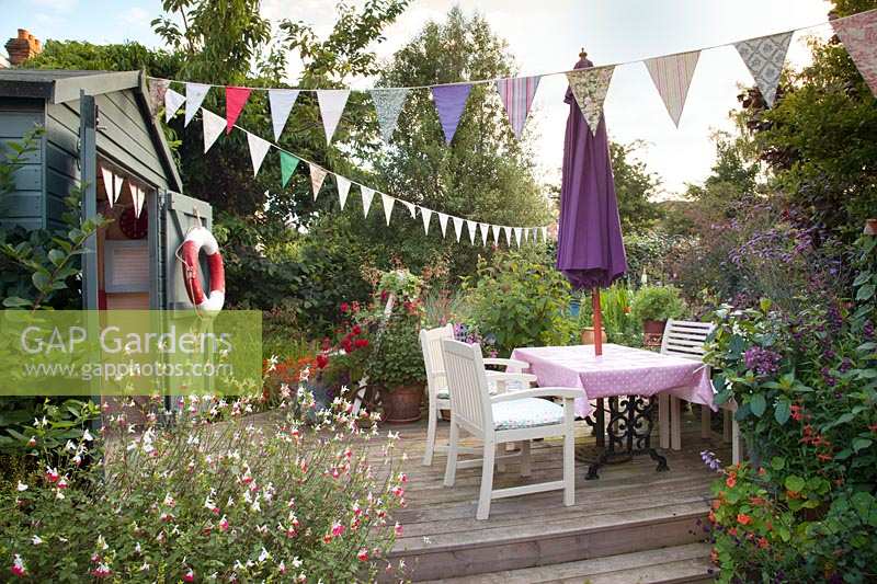 Coastal style garden, with beach inspired summerhouse, bunting and raised decking area. 