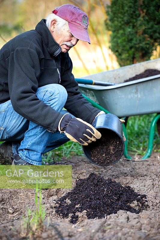 Adding bark to soil to prepare ground for planting.