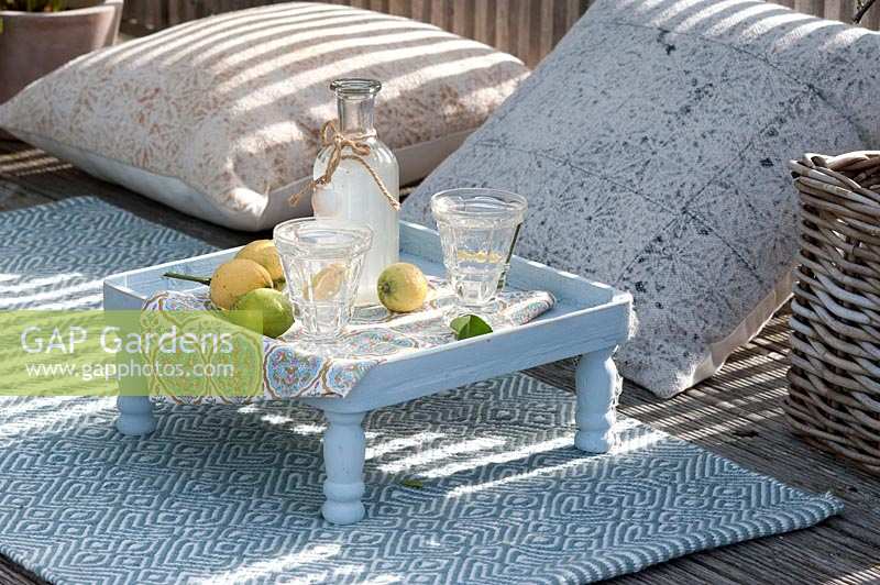 Small outdoor side table, surrounded by cushions for seating.  