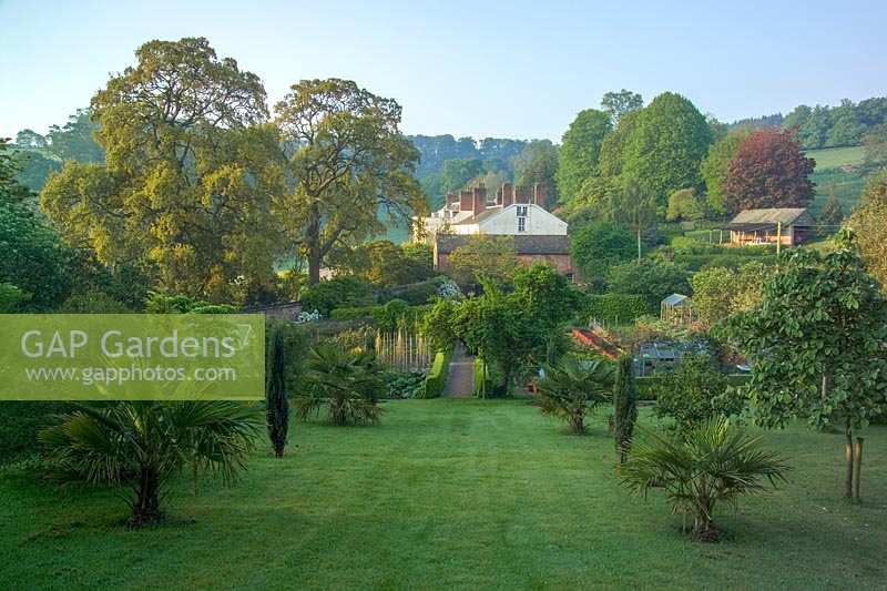 View across lawns and the kitchen garden to large country house, Bickham House, Devon,UK.  