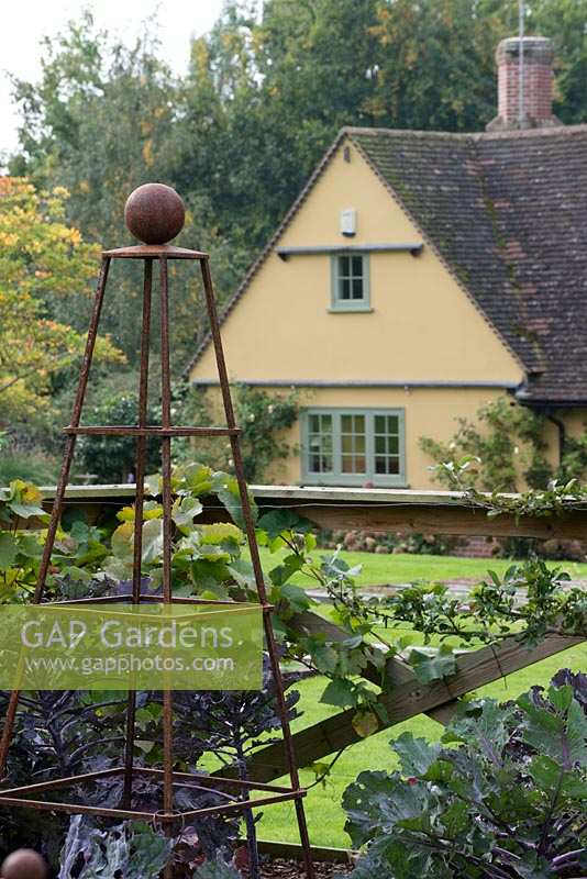 View of house from the vegetable garden with a metal pyramid support in late September. Brookside