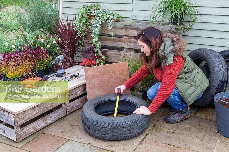 Woman taking measurements for base of tyre planter.