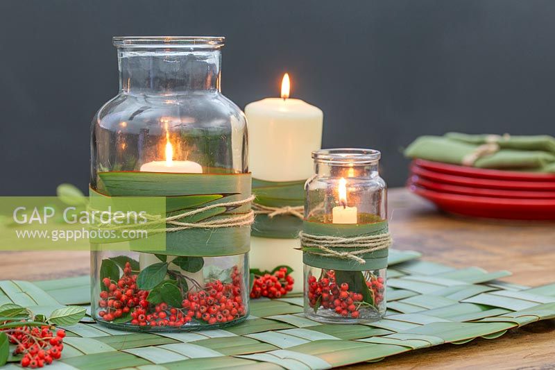 View of woven Phormium table mat and glass candle holders, decorated with Cotoneaster berries.