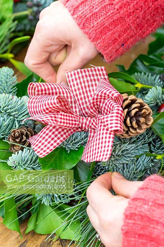 Securing wired ribbon bow to Christmas wreath.