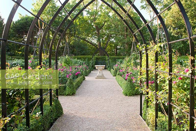 View through metal arbour into formal Rose Garden with sundial. Arundel Castle, West Sussex, UK. 