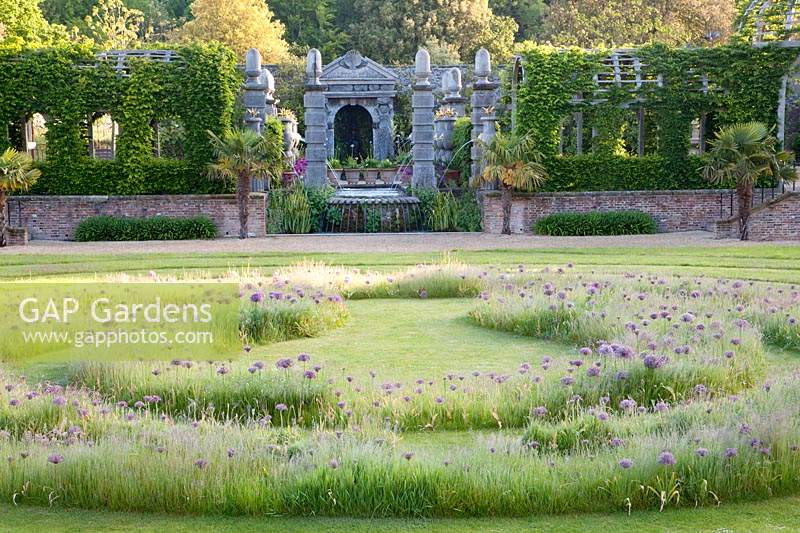 View from labyrinth planted with alliums to domed pergola and Italianate water feature. Arundel Castle, West Sussex, UK. 