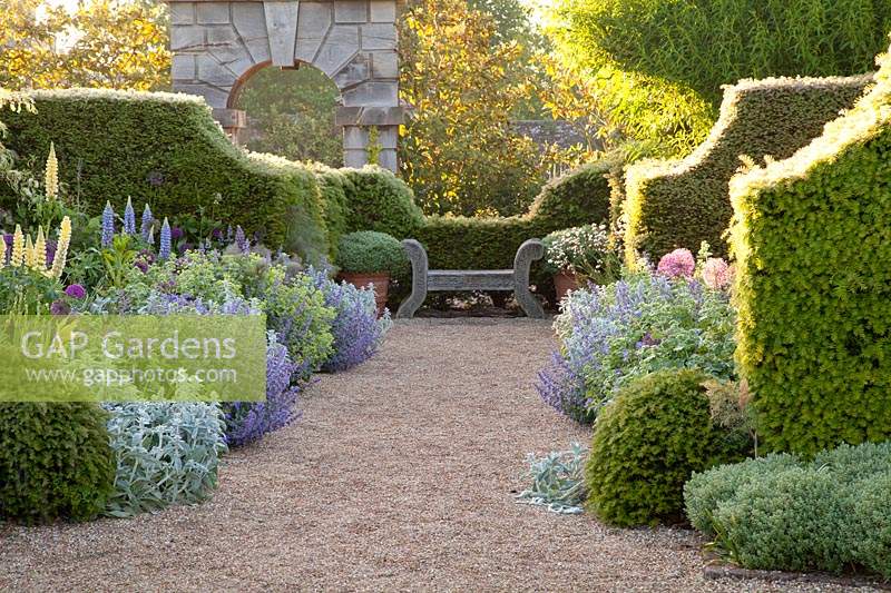 Summer borders with with seat and clipped yew hedges. Arundel Castle, West Sussex, UK