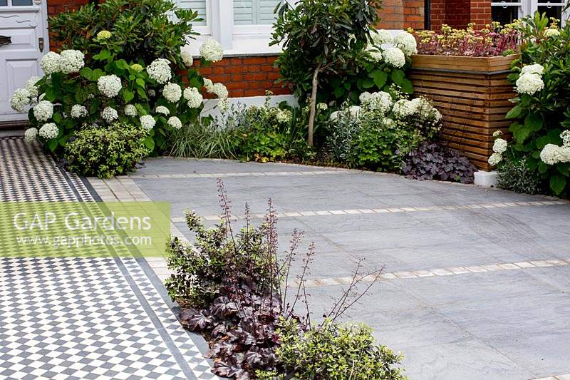 London house and front garden with black and white Victorian style tile path and tiled driveway. Designed by Kate Eyre Garden Design
