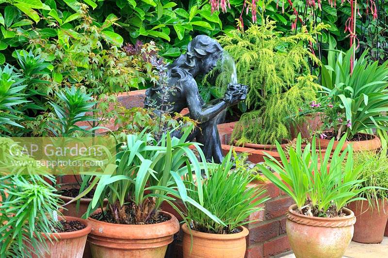 Water feature girl sculpture surrounded by pots. 