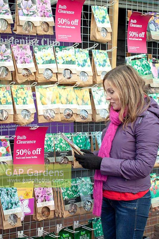 Woman buying tulip bulbs in a garden centre when they have been reduced in price. 