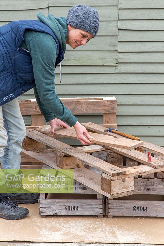 Woman lifting the loosened boards from pallet taking care with the exposed nails. 
