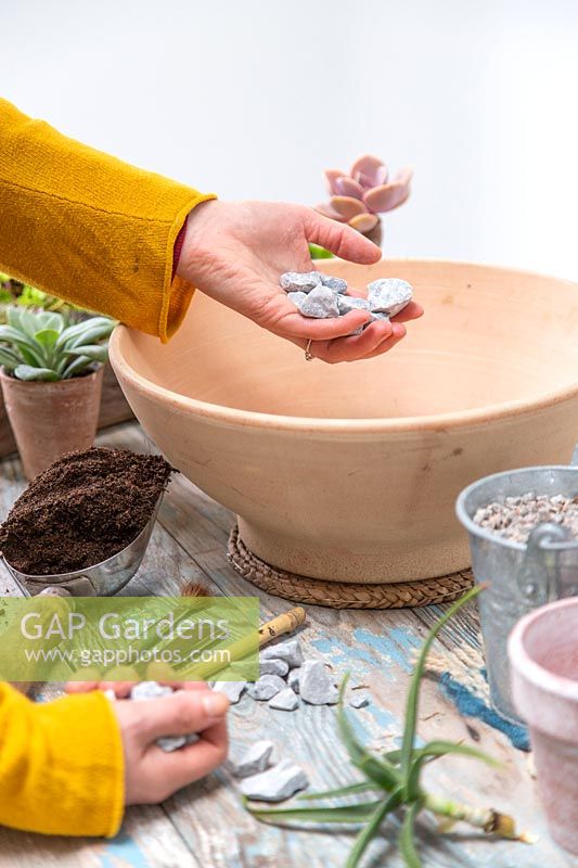 Woman adding stones to the bottom of shallow bowl